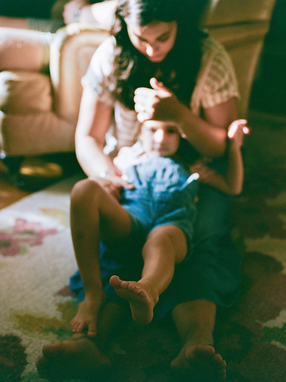 Soft focus images showing gentle family moments on a carpeted floor.