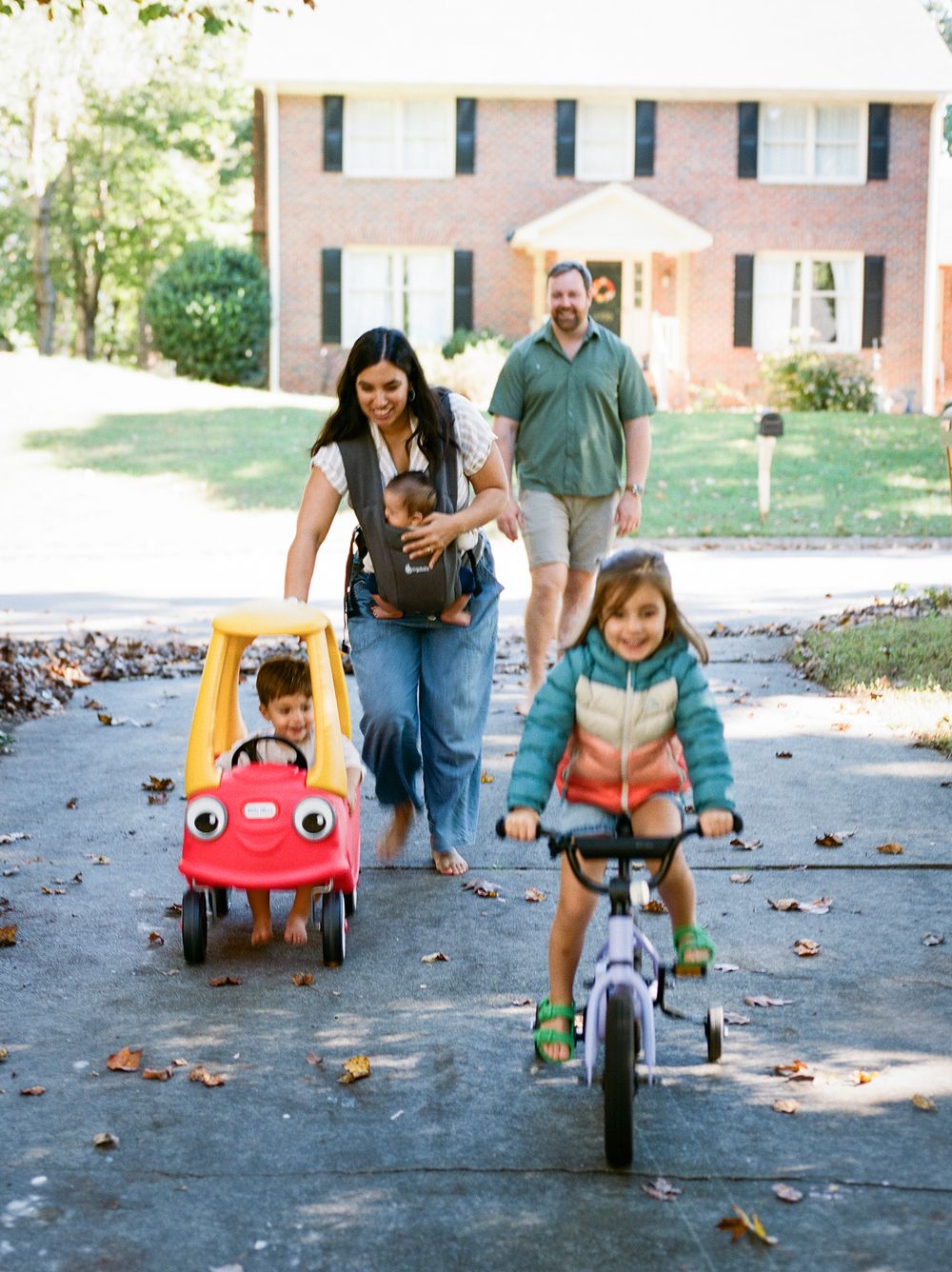 A series of photos showing a child riding a red toy car on a paved path with fallen autumn leaves.