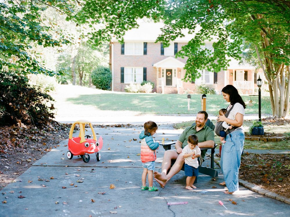 People sit and relax on a shaded sidewalk path during a sunny summer day.