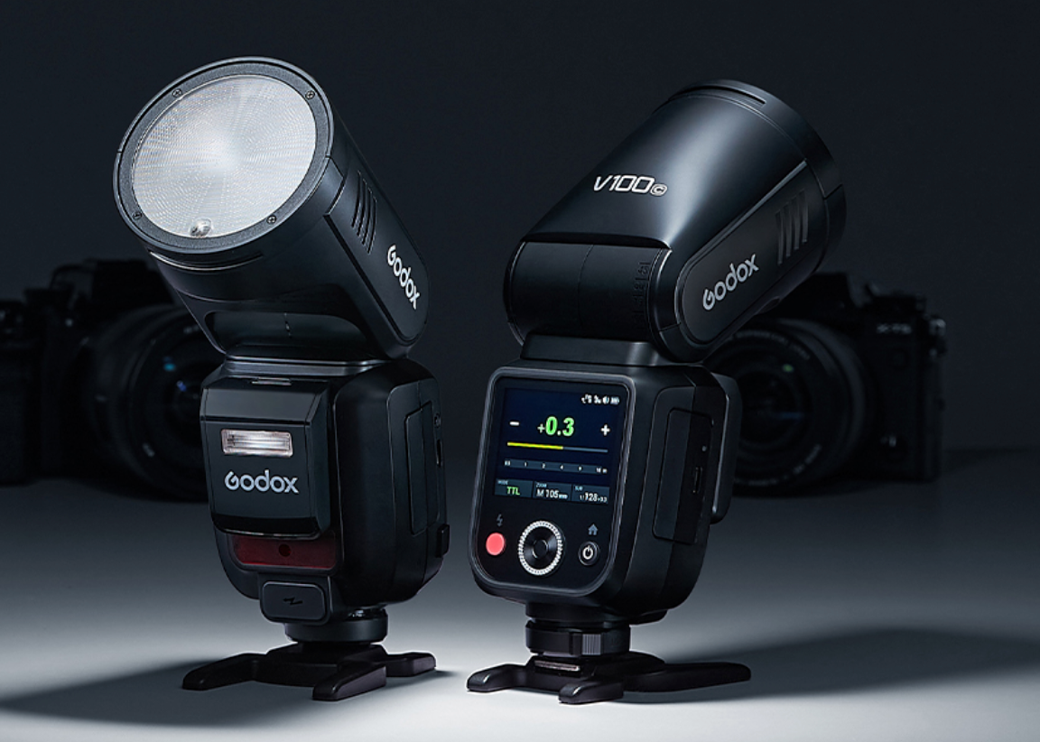 Professional camera flash units and speedlights displayed on dark background with dramatic lighting.