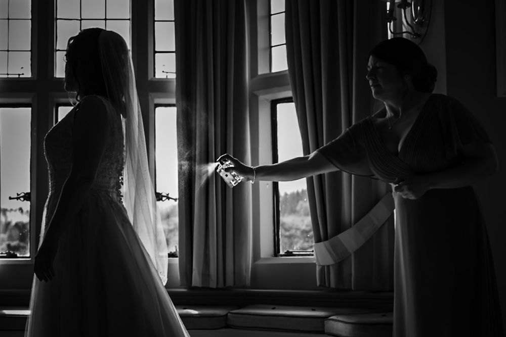 A silhouetted figure stands by a window in a dark room with natural light streaming in through the curtains.