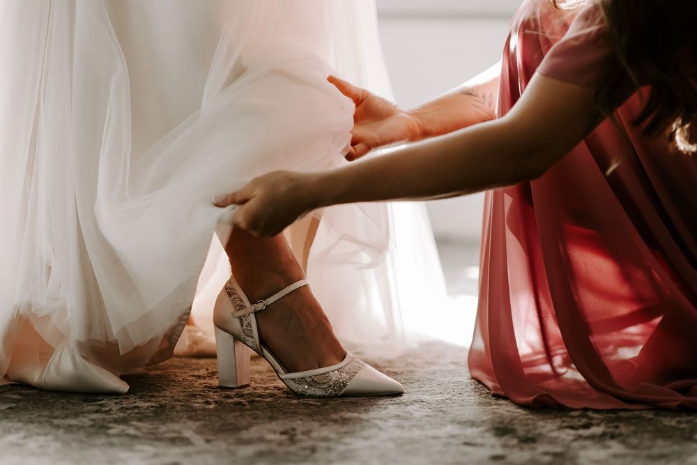 A row of wedding party members sitting in red and white dresses with hands resting on their laps during a ceremony.