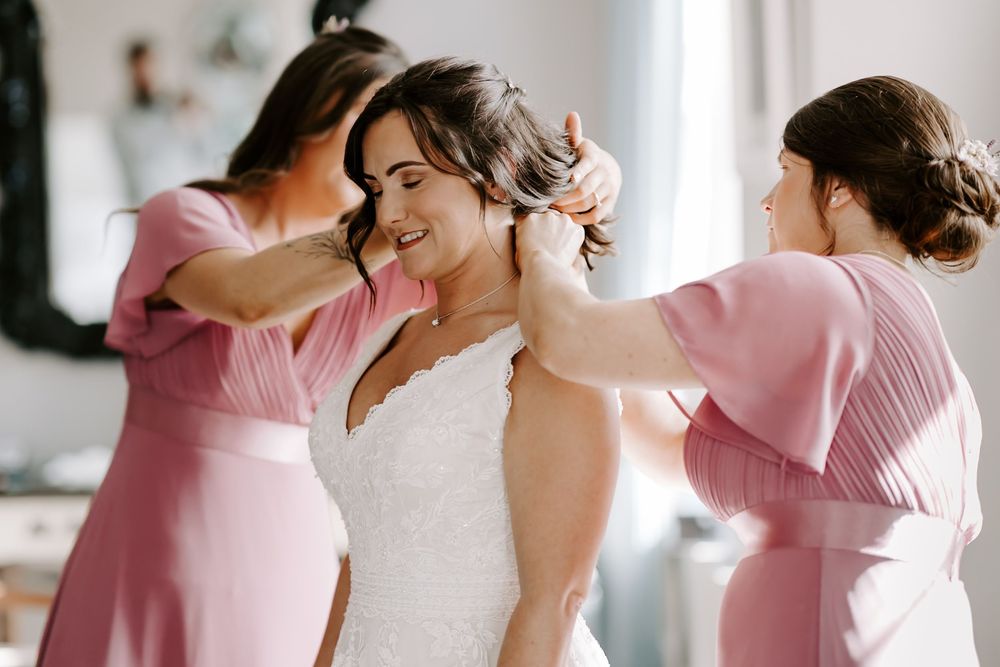A group of bridesmaids in pink dresses share joyful moments during a wedding celebration.
