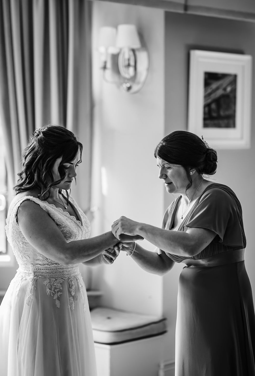 A series of black and white photos showing a bride getting help putting on her wedding dress during preparations.