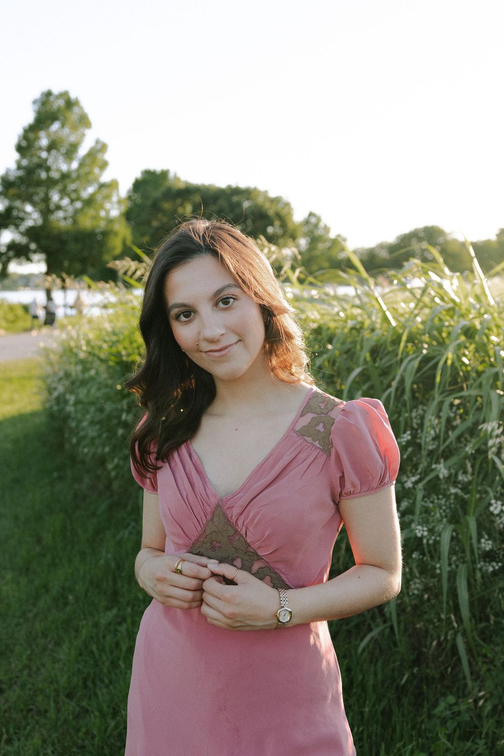 Pink dress with puff sleeves photographed in warm evening light against natural foliage.