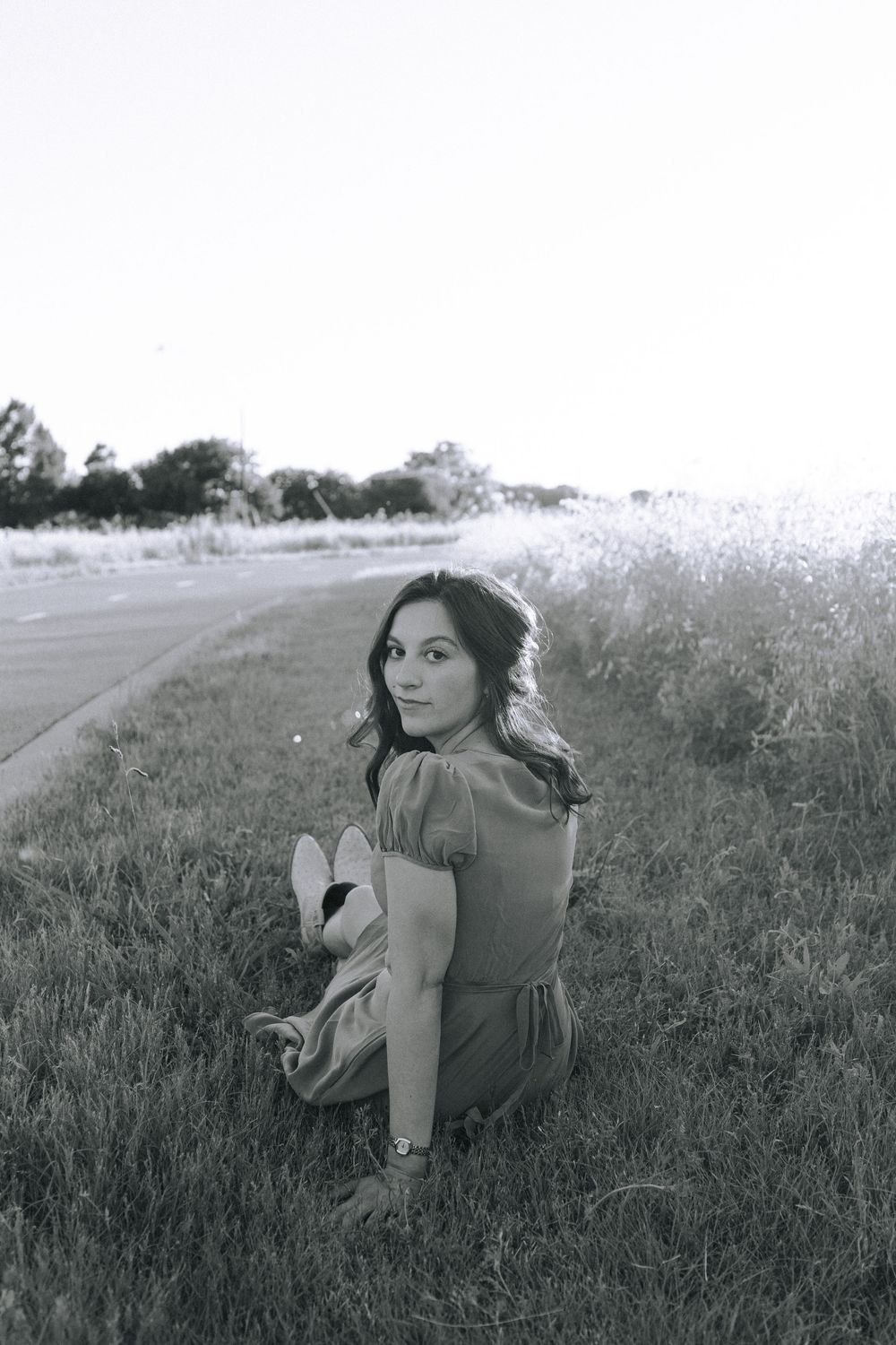 Black and white portrait of someone reclining in tall grass.