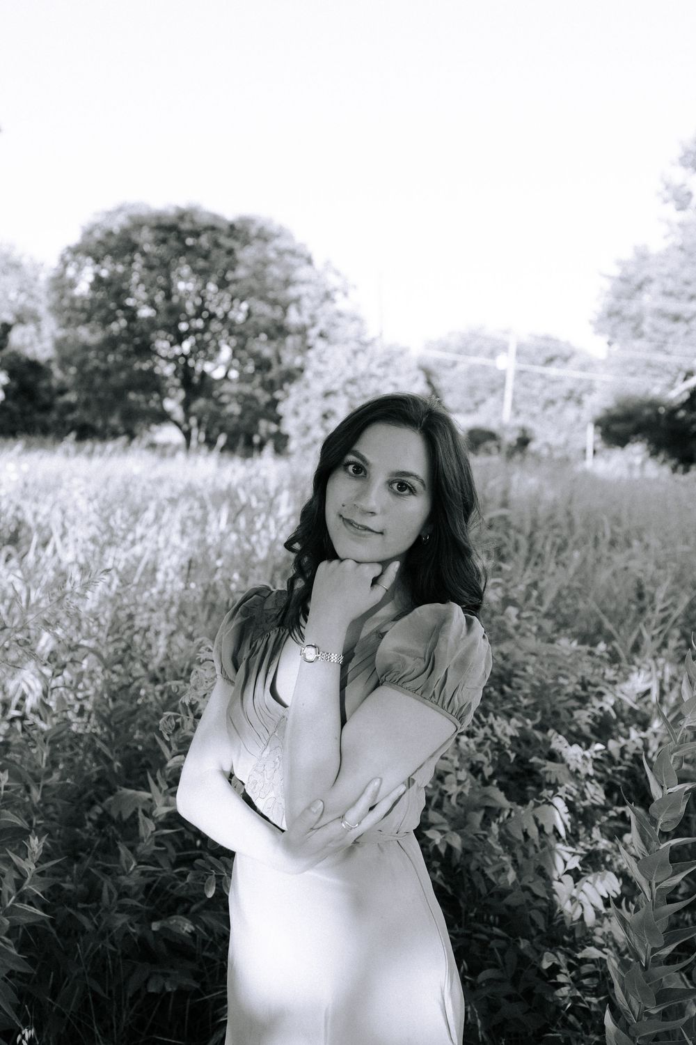 Monochrome portrait in a dreamy field setting with soft natural lighting.