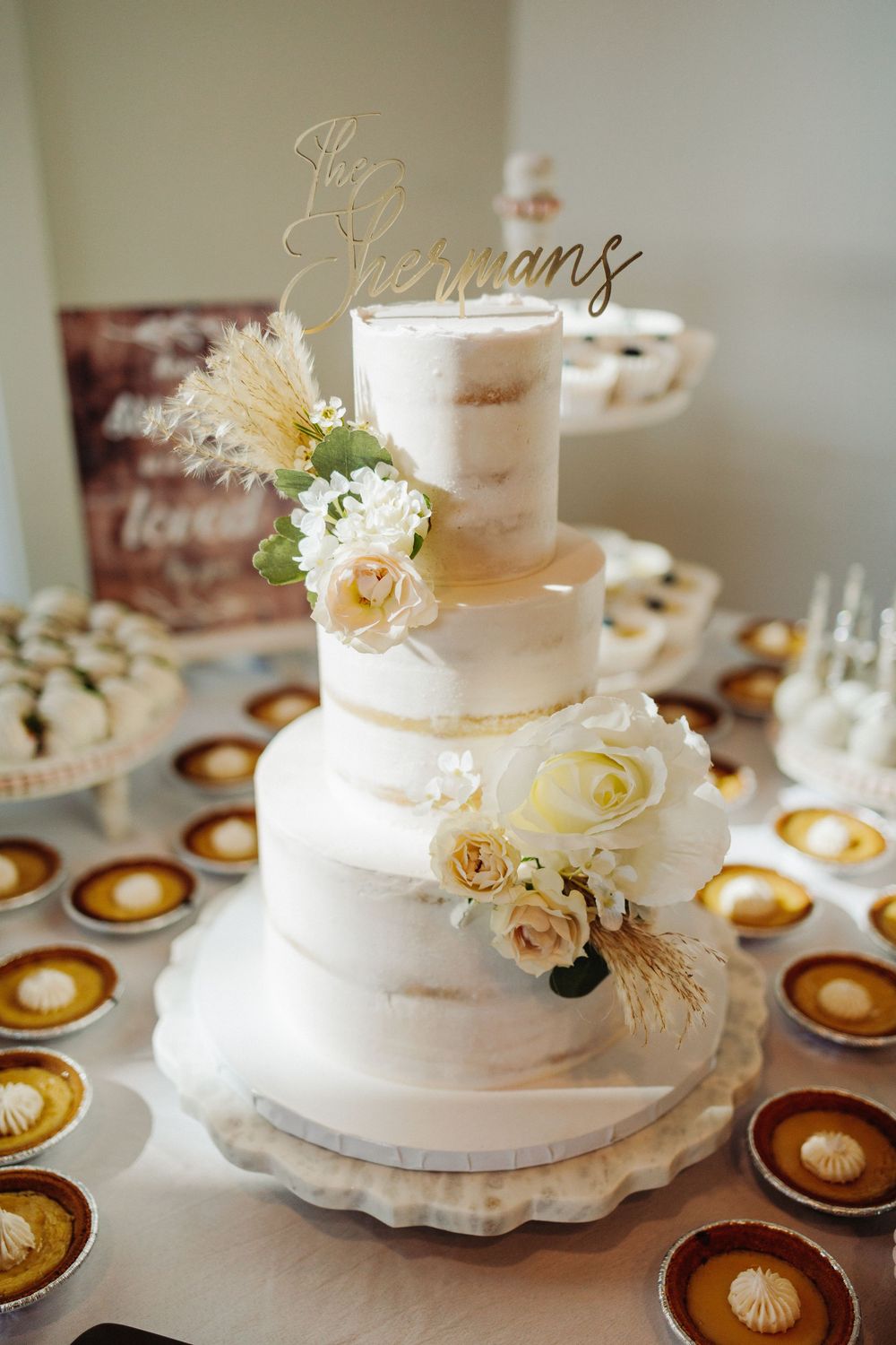 Elegant white wedding cake with fresh flowers decorated with peach and cream roses on display at reception.