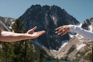 Dramatic mountain panorama shows seven merged photos of rocky peaks with snow patches against blue sky.