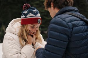 A couple share a tender moment wearing winter coats outdoors during what appears to be an emotional occasion.