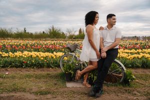 Couple posing with a vintage bicycle in a vibrant tulip field with yellow and red flowers in bloom.