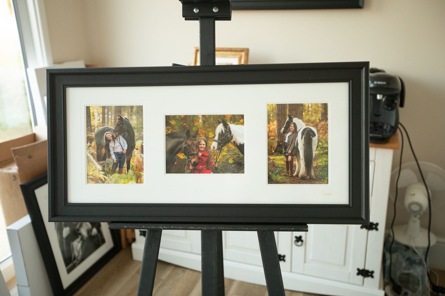A gallery wall with black frames displays various artwork and photographs in a bright, modern interior setting.