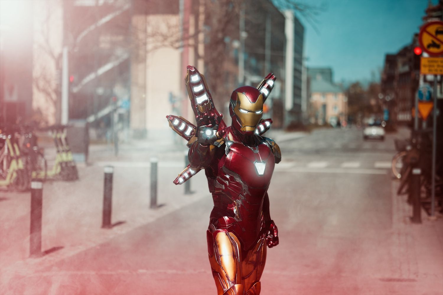 Iron Man suit stands triumphantly in a smoky urban street with arms raised in a victory pose.