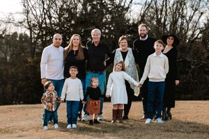 Group standing together outdoors in a brown grassy field with trees in background at sunset during an extended family session in Kearney, NE