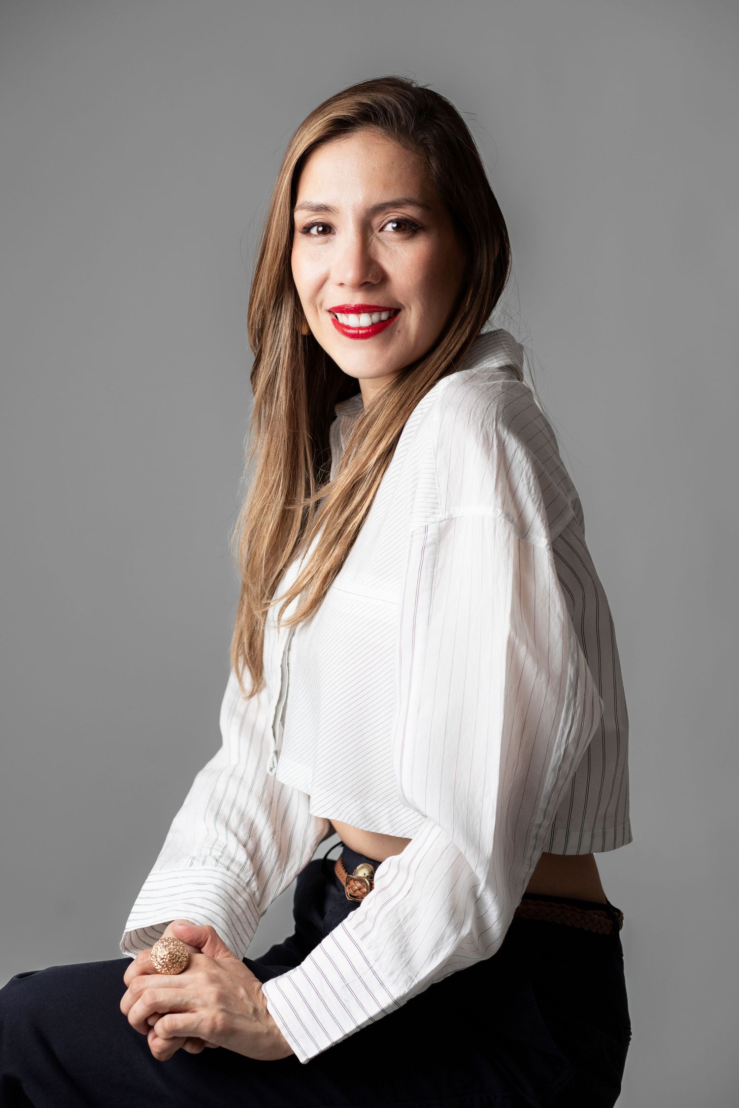 Casual portrait of person in white button-down shirt with long hair against gray background.