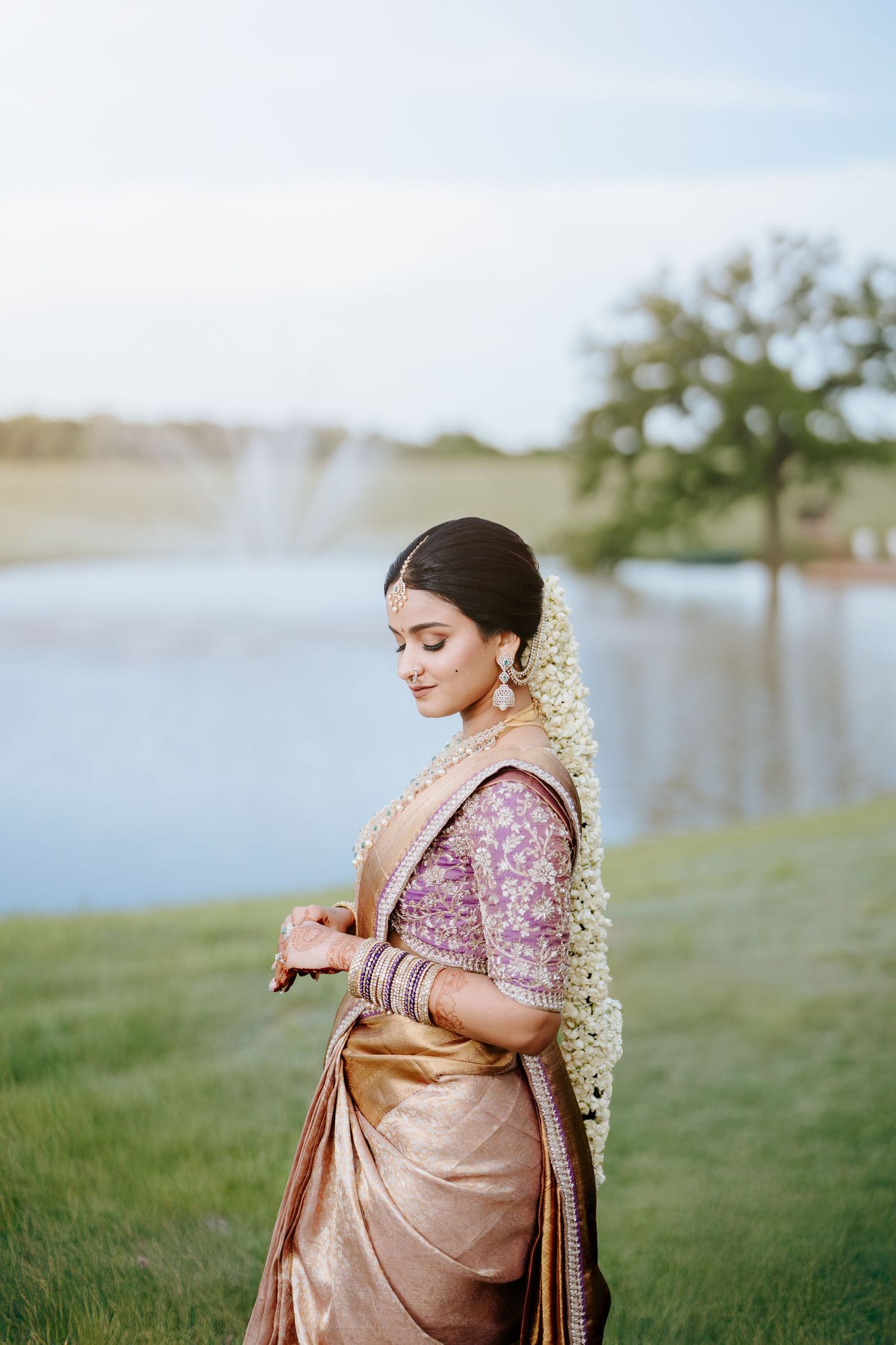 Couple sharing an intimate moment under floral wedding arch wearing traditional South Asian gold and cream attire.