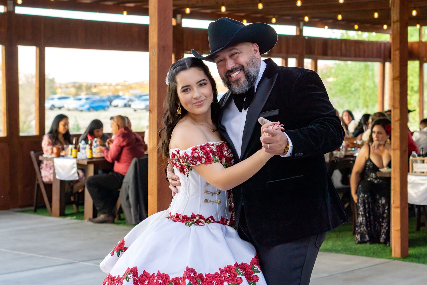 a father daughter dance at a quinceanera, in a waltz pose both smiling at the camera.