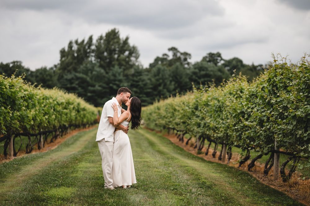 Wide landscape shots of a couple celebrating their engagement in a vineyard.