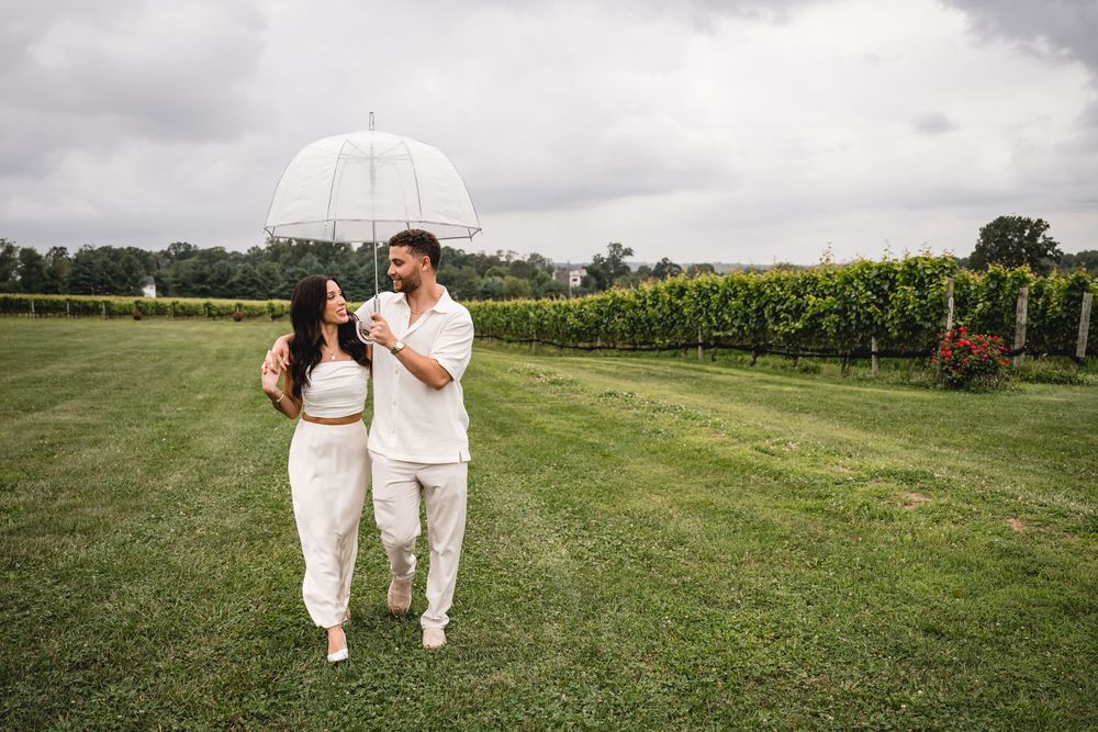Two people in white outfits walking together across a green field.