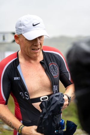 Athlete wearing Nike cap and sports gear checks monitoring device during endurance competition.