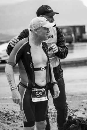 Triathlete wearing race number at transition area in black and white photography.