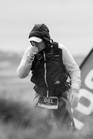 Semi-transparent series of black and white side-profile shots showing someone wearing a white jacket and black backpack.