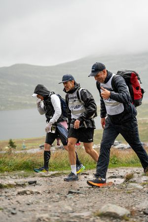 Group of hikers climbing rugged mountain path with backpacks and gear.