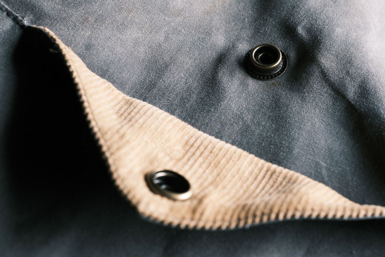 Close-up macro shot of black button-down shirt showing corduroy fabric texture and button detail.