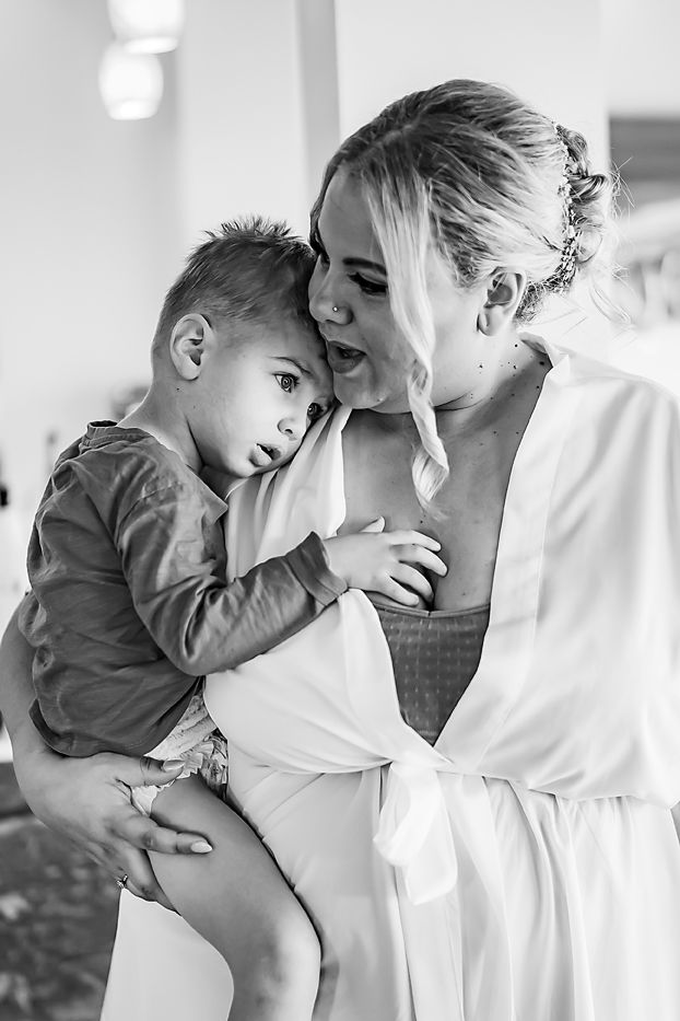 A tender black and white portrait capturing an intimate shared moment between a mother in a robe and young child.