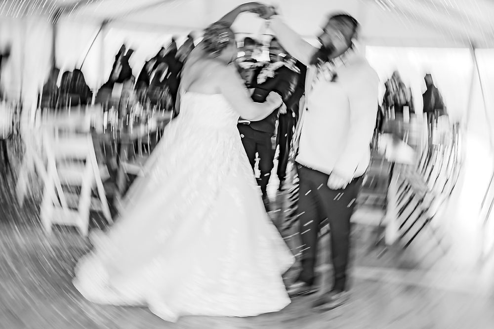 A blurred wedding dance photo shows a bride and groom spinning on the dance floor during their first dance.