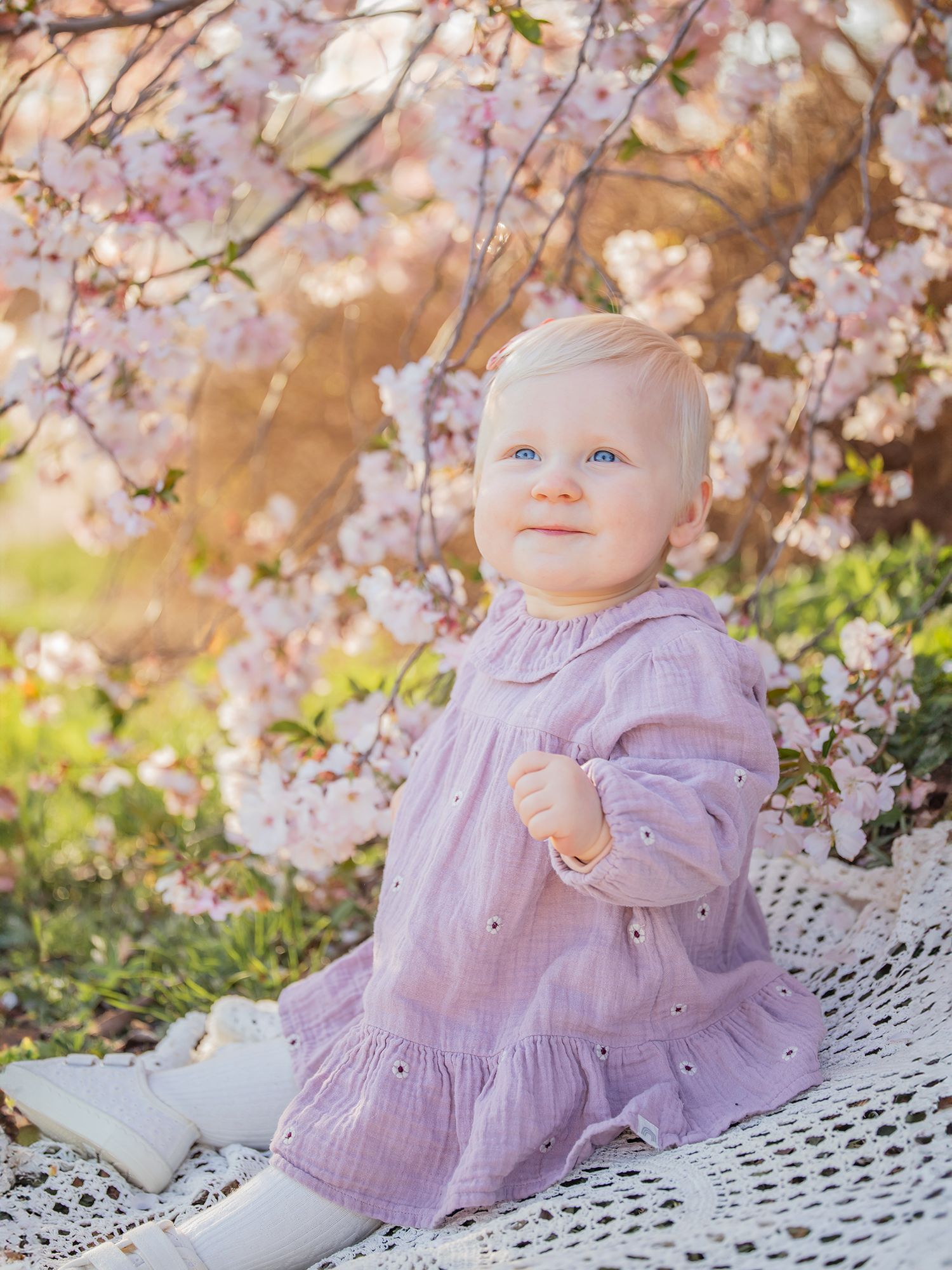 Bebis sitter på vacker filt under blommande träd i motljus med gullig newbieklänning, Barnfotografering i västerås, MemoriesbyM