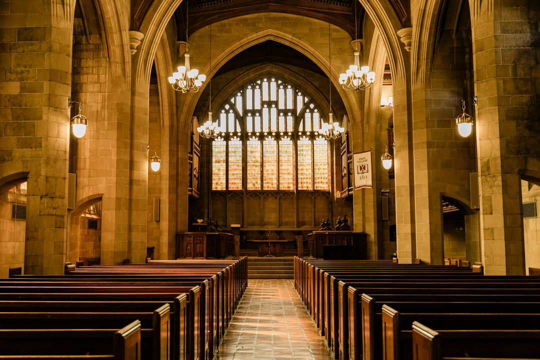 Empty Knox Chapel interior with glowing stained glass and pews before the Knox College wedding.