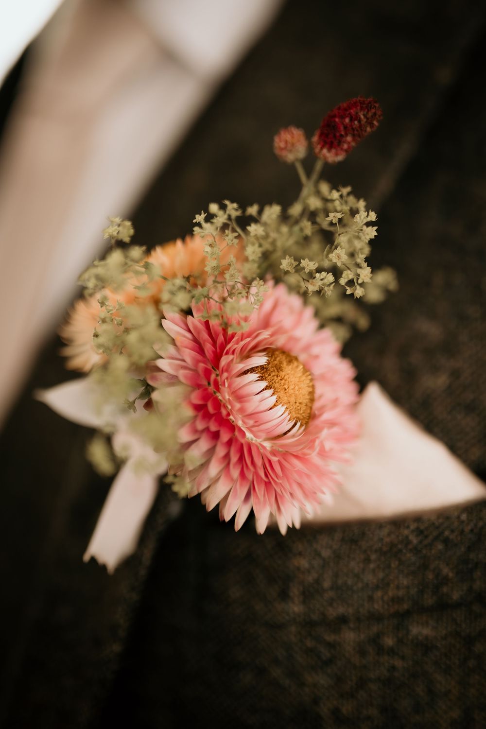 A delicate pink dahlia flower with baby's breath creates a romantic floral detail against a dark background.