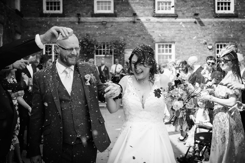 Black and white photo of wedding celebration with guests throwing confetti.