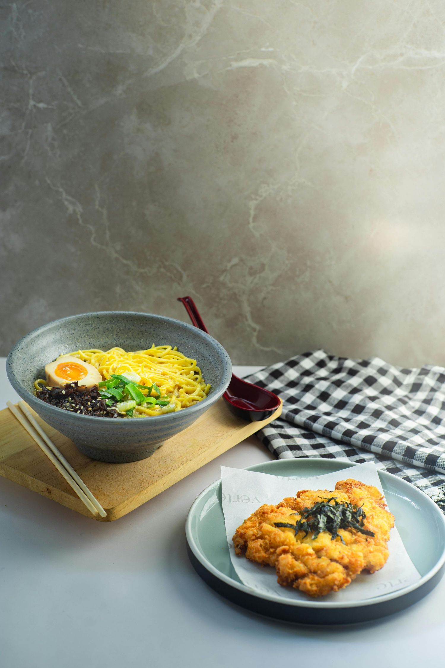Asian cuisine featuring ramen noodle soup and crispy katsu on separate plates.