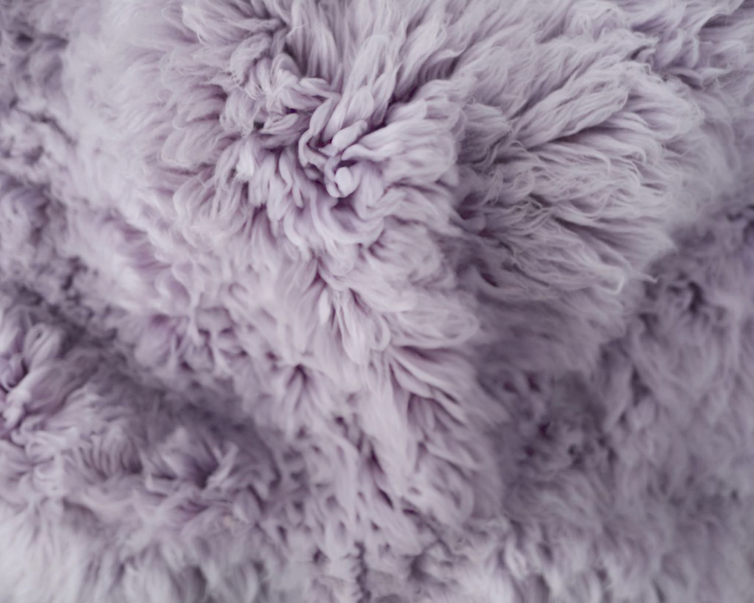 Close-up macro shot of pink shaggy fur or carpet with fluffy fibers creating a soft textured surface.
