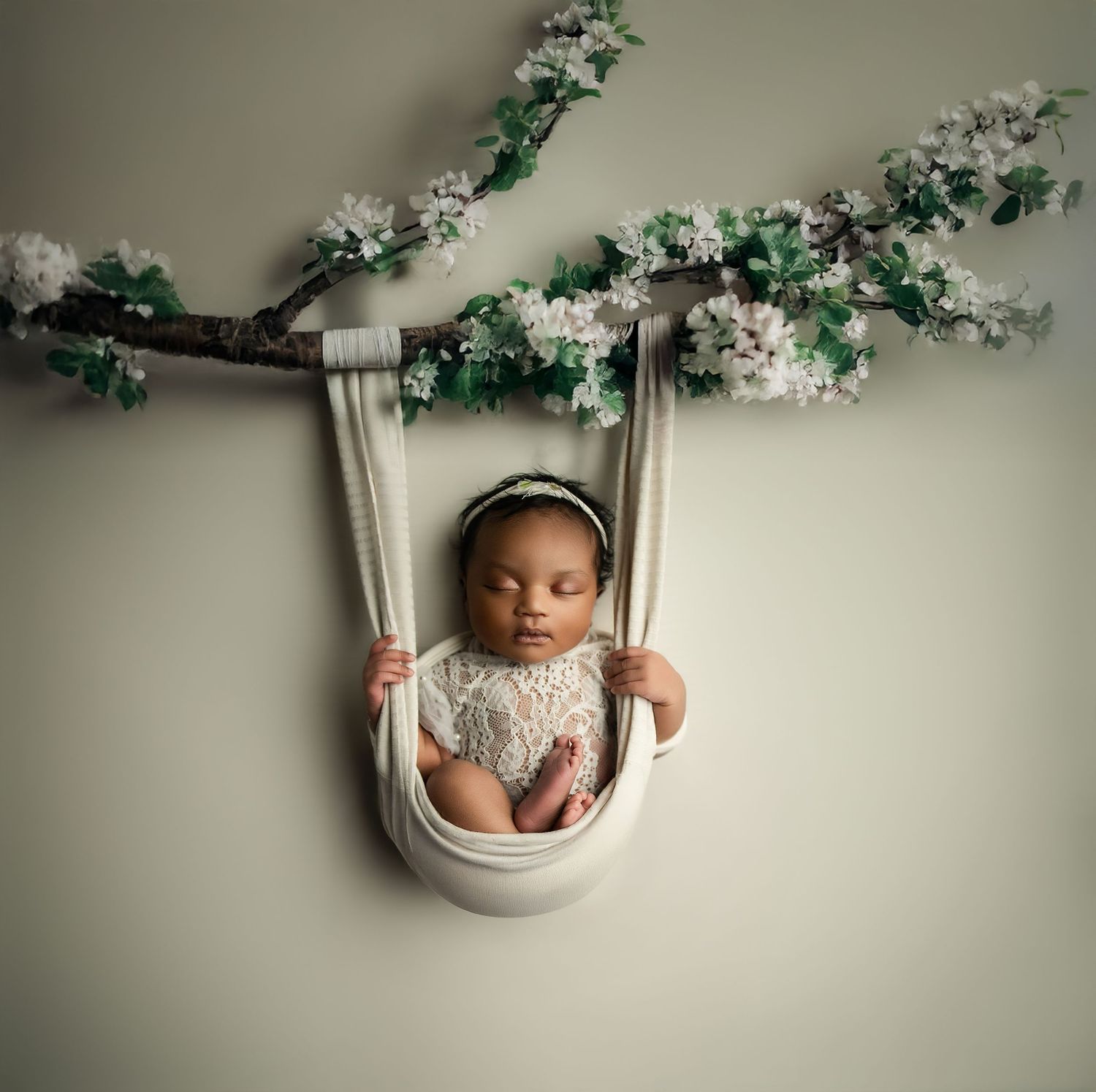 Adorable baby wearing hair bow nestles in soft brown tulle fabric with delicate polka dot pattern.