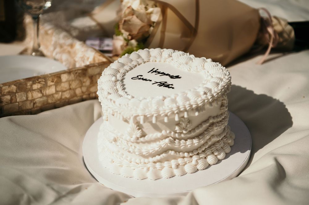 White wedding cake with delicate piped frosting details sits on display.