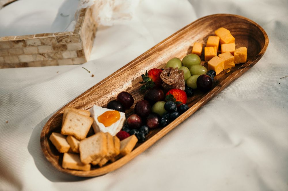 Wooden charcuterie boards filled with fruits, cheese, and appetizers on a white tablecloth.