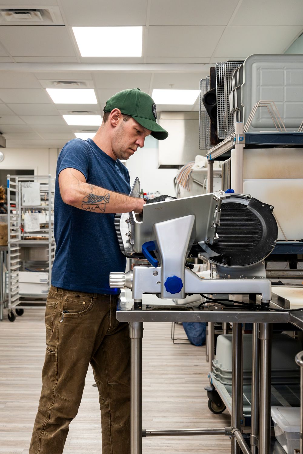 Baker operating a commercial flour mill machine in an industrial kitchen.