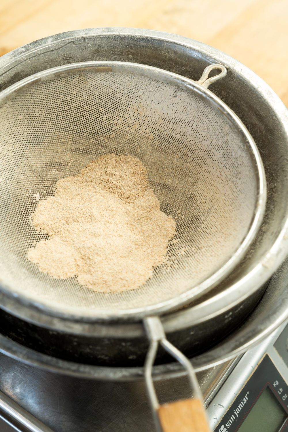 Close-up sequence showing powdery substance being sifted through a fine mesh strainer.
