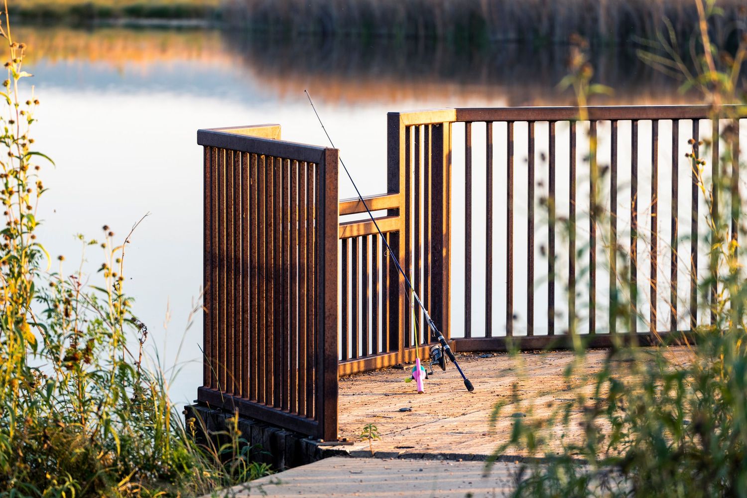 Wooden deck gate overlooking a serene lake at sunset.