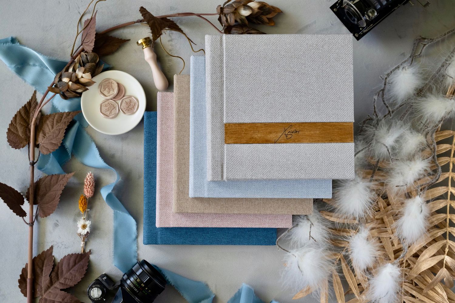 Various paper materials, ribbons, and decorative elements arranged in an artistic flatlay on a soft blue-tinted surface.