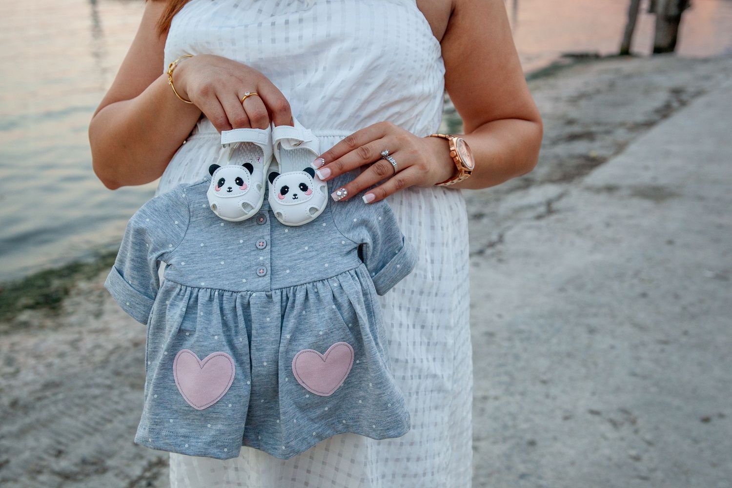 Close-up view of tiny baby clothes with heart patterns being held up.
