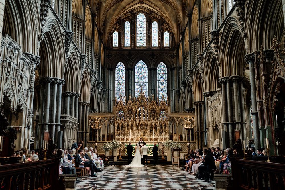 The wedding at Ely Cathedral features soaring arched windows, vaulted ceilings, and intricate Gothic stonework.