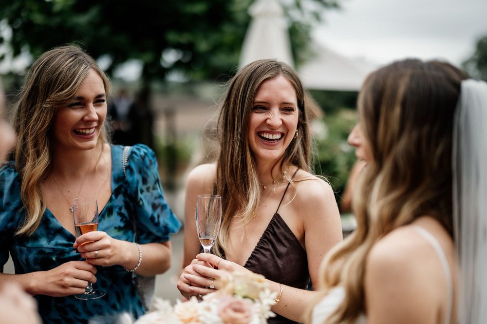 Group of friends enjoying drinks and laughter at a summer outdoor gathering.