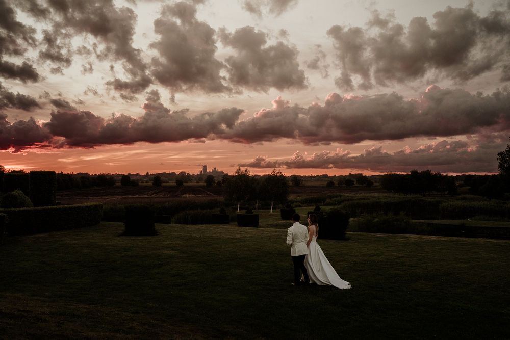 Dramatic sunset landscape with dark storm clouds rolling across rural farmland at The Old Hall as golden light breaks through the horizon.