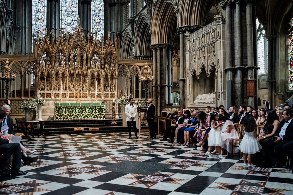 Ornate church altar and interior with black and white checkered floor during a wedding ceremony at Ely Cathedral.