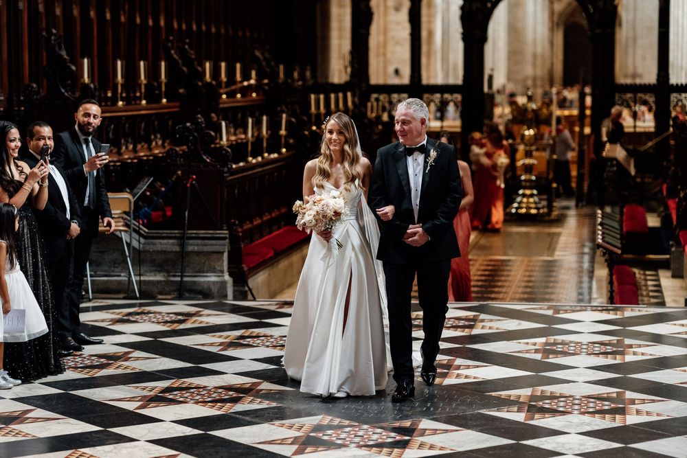 Elegant wedding ceremony in a historic Ely Cathedral with black and white checkered marble floors.