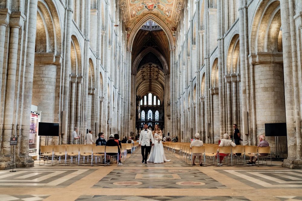 Gothic cathedral interior panorama showing ornate vaulted ceiling, stone columns and long nave in Ely Cathedral, England.